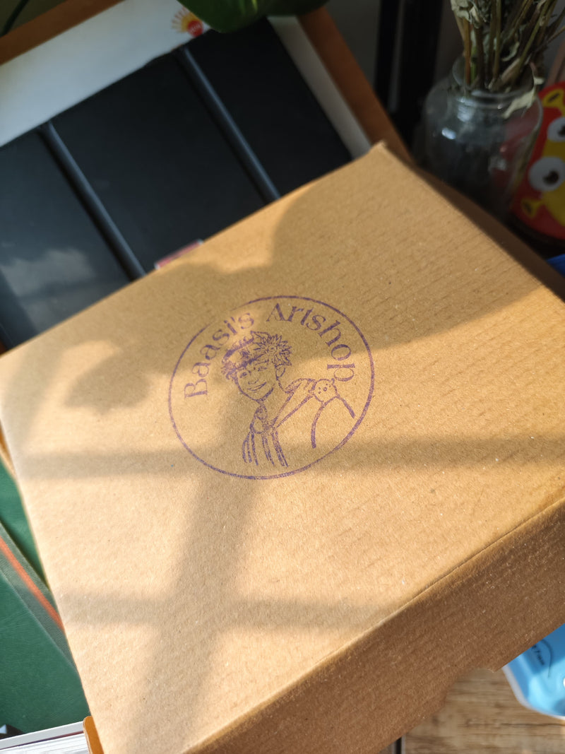 A kraft parcel stamped with the Baasi's Art Shop logo