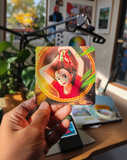 Hand holding a colorful card with an illustration of a person in a red outfit against a blurred indoor background.